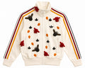 An off-white Adidas track jacket featuring Adidas Originals signature three stripes on the sleeves, embellished with embroidered bees, flowers, and leaves in red, orange, and black.