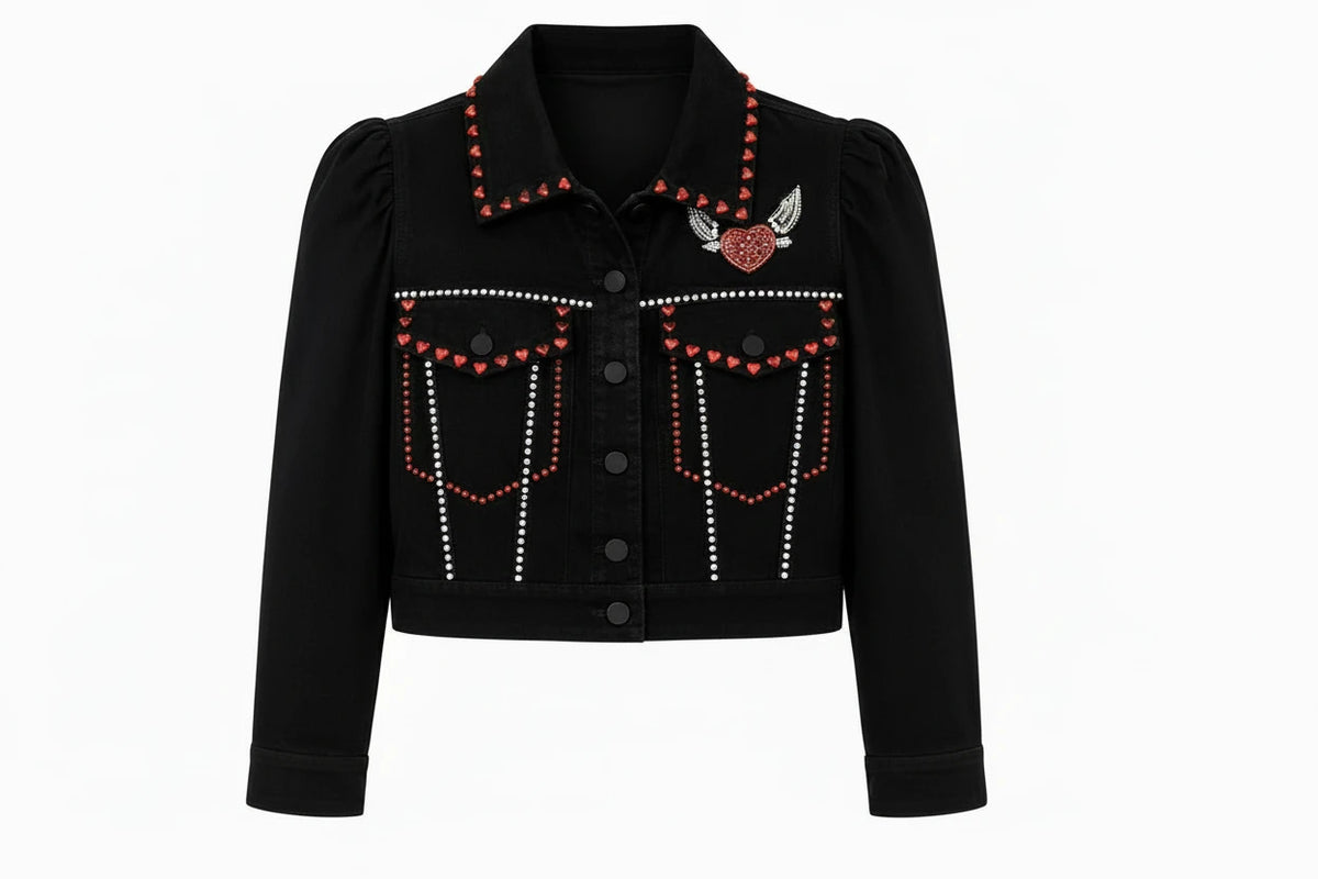 A black cropped denim jacket with red and white rhinestone embellishments, featuring a winged heart patch on the chest, on a solid white background.